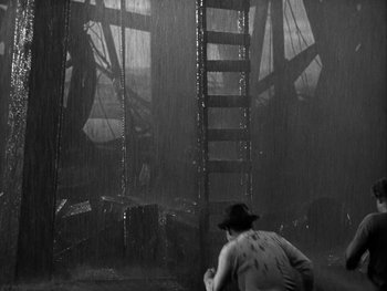 Movie still from “Boom Town” (1940), directed by Jack Conway – A man in a cowboy hat is standing in front of a ladder; Wide shot, Low angle