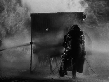 Movie still from “Boom Town” (1940), directed by Jack Conway – A man is spraying water on a fire hydrant; Wide shot, Low angle