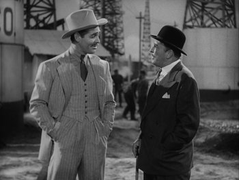 Movie still from “Boom Town” (1940), directed by Jack Conway – Two men in suits talking to each other in an oil field; Medium shot, Over the shoulder angle
