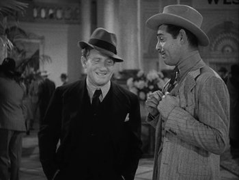 Movie still from “Boom Town” (1940), directed by Jack Conway – Two men in hats and suits are talking; Medium shot, High angle