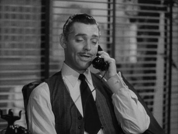 Movie still from “Boom Town” (1940), directed by Jack Conway – A man talking on a phone while sitting in a chair; Close Up shot, High angle