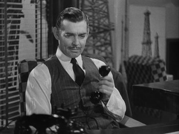 Movie still from “Boom Town” (1940), directed by Jack Conway – A man sitting in a chair holding a remote control; Medium shot, High angle