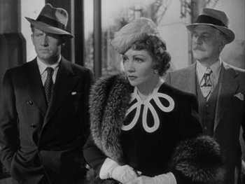Movie still from “Boom Town” (1940), directed by Jack Conway – An old photo of a woman in a fur coat with two men in a suit; Medium shot, Over the shoulder angle