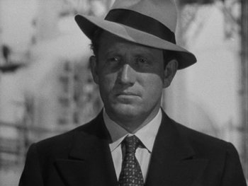 Movie still from “Boom Town” (1940), directed by Jack Conway – A man wearing a suit and hat in a black and white photo; Close Up shot, Low angle