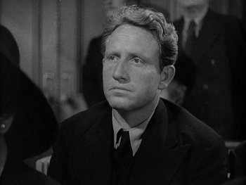 Movie still from “Boom Town” (1940), directed by Jack Conway – A man in a suit and tie sitting in front of a camera; Close Up shot, High angle