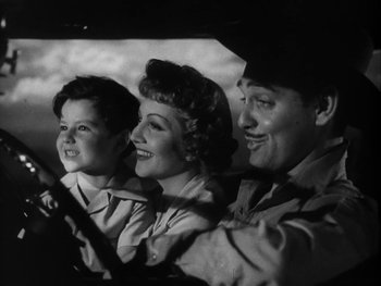 Movie still from “Boom Town” (1940), directed by Jack Conway – An old black and white photo of a man , woman , and child in a car; Medium shot, Low angle