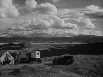 Movie still from “Boom Town” (1940), directed by Jack Conway – An old photo of an old car and a truck in a field; Extreme Wide shot, High angle