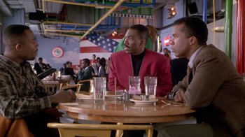 Movie still from “Boomerang” (1992), directed by Reginald Hudlin – A group of people sitting at a table with drinks; Medium shot, Over the shoulder angle