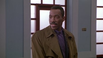 Movie still from “Boomerang” (1992), directed by Reginald Hudlin – A man wearing a brown jacket and purple shirt; Close Up shot, Over the shoulder angle