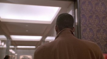 Movie still from “Boomerang” (1992), directed by Reginald Hudlin – A man wearing a brown jacket standing in a hallway; Close Up shot, Over the shoulder angle