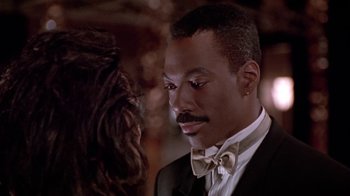 Movie still from “Boomerang” (1992), directed by Reginald Hudlin – A person wearing a suit and a bow tie; Close Up shot, Over the shoulder angle