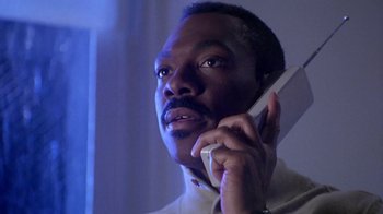 Movie still from “Boomerang” (1992), directed by Reginald Hudlin – A man talking on a cell phone in a room; Close Up shot, Low angle