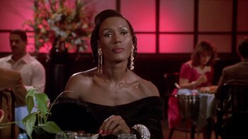 Movie still from “Boomerang” (1992), directed by Reginald Hudlin – A woman in a black dress sitting in front of a table; Close Up shot, Over the shoulder angle