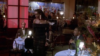 Movie still from “Boomerang” (1992), directed by Reginald Hudlin – A group of people sitting at tables in a room; Medium shot, Over the shoulder angle