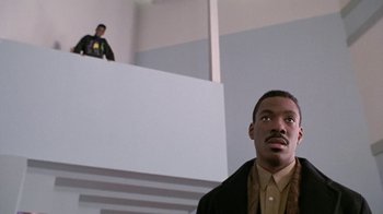 Movie still from “Boomerang” (1992), directed by Reginald Hudlin – A man standing in front of another man on a staircase; Wide shot, Low angle