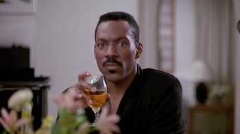 Movie still from “Boomerang” (1992), directed by Reginald Hudlin – A man holding a glass of wine while sitting down; Close Up shot, Low angle
