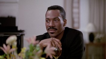 Movie still from “Boomerang” (1992), directed by Reginald Hudlin – A man sitting at a table holding a glass of wine; Close Up shot, Over the shoulder angle