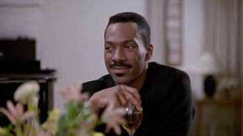 Movie still from “Boomerang” (1992), directed by Reginald Hudlin – A man sitting at a table holding a glass of wine; Close Up shot, Low angle