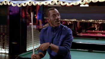 Movie still from “Boomerang” (1992), directed by Reginald Hudlin – A man holding a pool cue in his hand; Medium shot, Over the shoulder angle