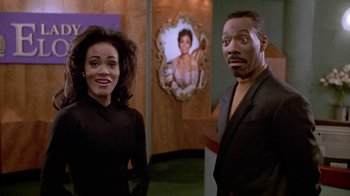 Movie still from “Boomerang” (1992), directed by Reginald Hudlin – A man and a woman standing next to each other in a room; Medium shot, Over the shoulder angle