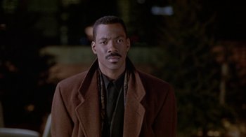 Movie still from “Boomerang” (1992), directed by Reginald Hudlin – A man in a brown coat and a black shirt; Close Up shot, Low angle