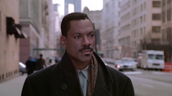 Movie still from “Boomerang” (1992), directed by Reginald Hudlin – A man in a coat and tie standing in the street; Close Up shot, Low angle