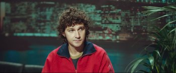 Movie still from “Borg vs. McEnroe” (2017), directed by Janus Metz – A man with curly brown hair wearing a red jacket; Close Up shot, High angle