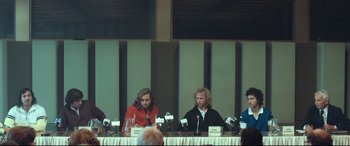 Movie still from “Borg vs. McEnroe” (2017), directed by Janus Metz – A group of people sitting at a table with microphones; Medium shot, Low angle