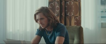 Movie still from “Borg vs. McEnroe” (2017), directed by Janus Metz – A man with long brown hair sitting on a chair; Medium shot, Over the shoulder angle