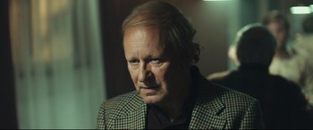 Movie still from “Borg vs. McEnroe” (2017), directed by Janus Metz – An older man in a jacket looking at the camera; Close Up shot, Over the shoulder angle