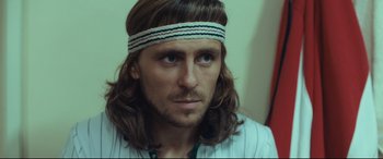 Movie still from “Borg vs. McEnroe” (2017), directed by Janus Metz – A person with long hair wearing a headband; Close Up shot, Over the shoulder angle