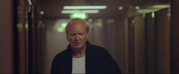 Movie still from “Borg vs. McEnroe” (2017), directed by Janus Metz – An older man in a white shirt and a black jacket; Close Up shot, Over the shoulder angle