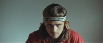 Movie still from “Borg vs. McEnroe” (2017), directed by Janus Metz – A person with long hair wearing a headband; Close Up shot, Low angle