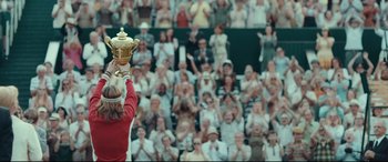 Movie still from “Borg vs. McEnroe” (2017), directed by Janus Metz – A woman holding a trophy in front of a crowd; Medium shot, Low angle