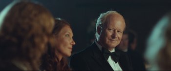 Movie still from “Borg vs. McEnroe” (2017), directed by Janus Metz – An older man in a tuxedo and a woman in a black suit; Close Up shot, Over the shoulder angle