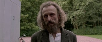 A man with long hair and a beard is wearing a suit