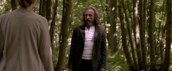 A man with long hair and a beard standing in the woods