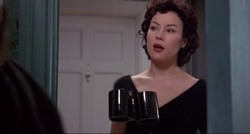 Movie still from “Bound” (1996), directed by Lilly Wachowski – A woman in a black dress holding two black cups; Medium shot, Over the shoulder angle