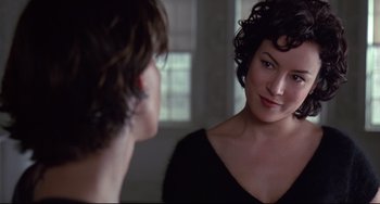 Movie still from “Bound” (1996), directed by Lilly Wachowski – A woman looking into a mirror while standing next to a man; Close Up shot, Over the shoulder angle