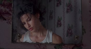 Movie still from “Bound” (1996), directed by Lilly Wachowski – A woman sitting on a bed looking at the camera; Close Up shot, Low angle
