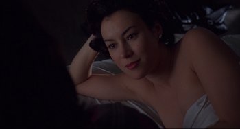 Movie still from “Bound” (1996), directed by Lilly Wachowski – A beautiful woman laying on top of a bed in a room; Close Up shot, Over the shoulder angle