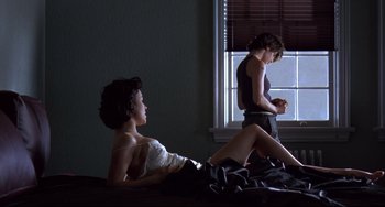 Movie still from “Bound” (1996), directed by Lilly Wachowski – A man and a woman sitting on a bed in front of a window; Wide shot, Low angle