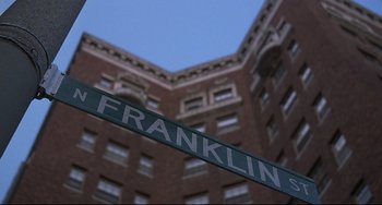 Movie still from “Bound” (1996), directed by Lilly Wachowski – A street sign in front of a brick building; Extreme Close Up shot, Low angle
