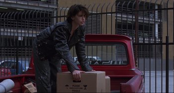 Movie still from “Bound” (1996), directed by Lilly Wachowski – A woman in a leather jacket holding a box; Medium shot, Low angle