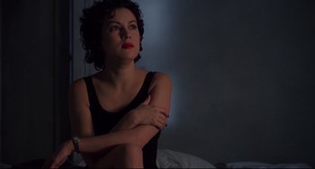Movie still from “Bound” (1996), directed by Lilly Wachowski – A woman sitting on top of a bed with her arms crossed; Close Up shot, High angle