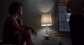 Movie still from “Bound” (1996), directed by Lilly Wachowski – A woman sitting on a chair next to a lamp; Medium shot, Low angle