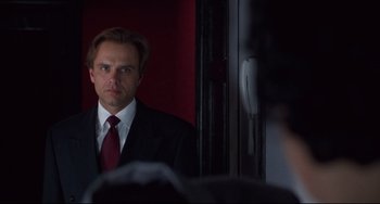 Movie still from “Bound” (1996), directed by Lilly Wachowski – A man wearing a suit and tie looking at himself in a mirror; Close Up shot, Over the shoulder angle