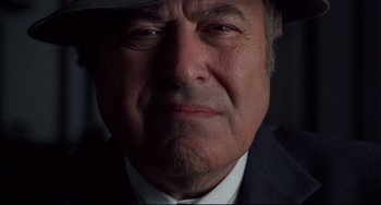 Movie still from “Bound” (1996), directed by Lilly Wachowski – An older man wearing a suit and a hat; Extreme Close Up shot, Low angle
