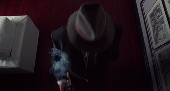 Movie still from “Bound” (1996), directed by Lilly Wachowski – A man in a fedora smoking a cigarette; Extreme Close Up shot, Overhead angle