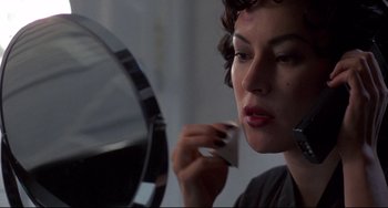 Movie still from “Bound” (1996), directed by Lilly Wachowski – A woman is looking in the mirror while putting makeup on; Close Up shot, Over the shoulder angle